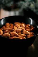 Enjoying a bowl of roasted almonds on a dark background for a healthy snack or culinary delight