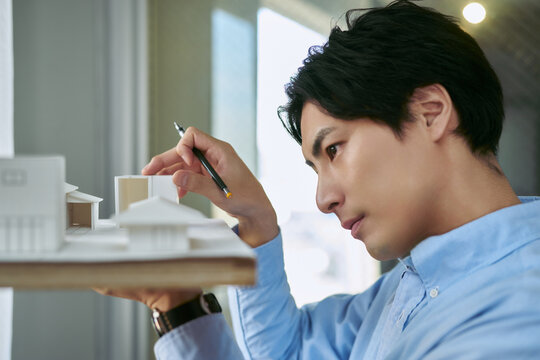 大学の工学部の建築学科の教室で建築模型を作り建築の設計を学ぶ男性の学生