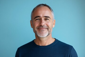 Obraz premium A happy middle aged man smiles against a blue background