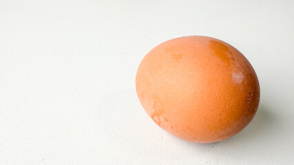 Brown egg on white surface, symbolizing Easter, natural cooking ingredient, simple organic food...