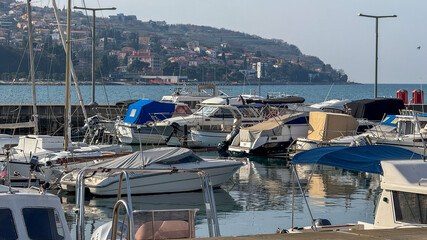 Boats docked in a serene marina with a coastal town backdrop, nautical travel, summer vacation