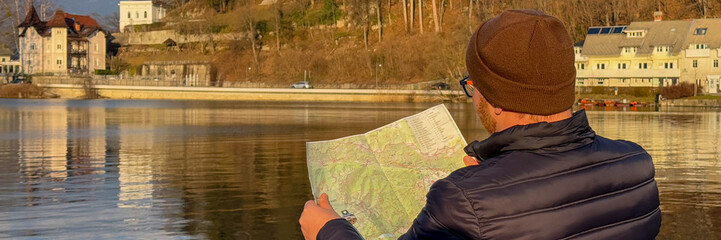 A man reading a map by the lakeside, outdoor adventure, autumn travel planning, exploration