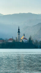 Scenic view of Lake Bled with church, Slovenia travel destination, serene nature, spiritual retreat 
