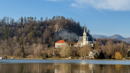 Fototapeta premium Peaceful lakeside view of St Marys Church surrounded by trees, reflecting tranquility, European architecture, serene natural landscape