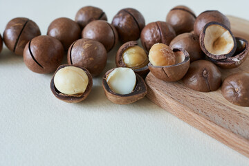 Macadamia nuts in a wooden stand on a light coloured background.