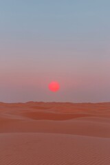 Obraz premium A serene desert landscape at sunset, showcasing soft dunes and a warm, glowing sun.