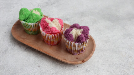Colorful Bolu Kukus (Sponge Cake), made from flour, tapioca flour, egg and sugar. Served on wooden plate isolated on grey background. Indonesian traditional snack