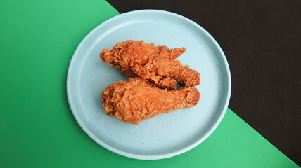 crispy kentucky fried chicken in a blue plate on green black background