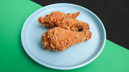 crispy kentucky fried chicken in a blue plate on green black background