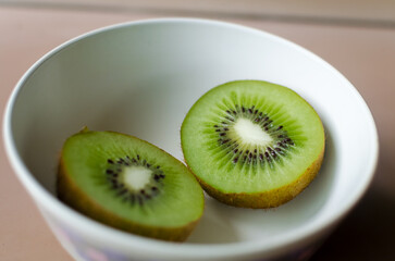 A closeup of a sliced kiwi fruit in a white bowl