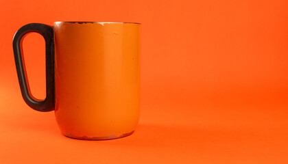 an orange cup whose paint has started to peel off, isolated in orange