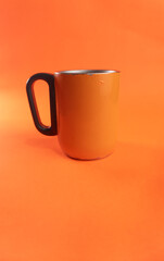 an orange cup whose paint has started to peel off, isolated in orange