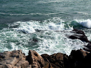 Majestic ocean waves crash against rocky coastline at sunset
