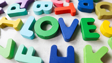 wooden blocks text with text love isolated on grey and alphabet background