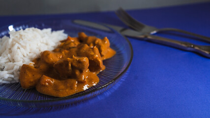 Delicious chicken curry served with fluffy white rice on a blue table setting during dinner time