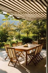 Fototapeta premium Outdoor dining area with wooden table and chairs under striped awning in lush garden setting, ideal for gatherings and backyard entertaining.