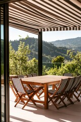Fototapeta premium Outdoor dining space with wooden table and chairs under awning, surrounded by greenery and mountains, perfect for summer entertaining and relaxation