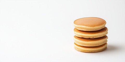 A stack of golden, round pancakes sits on a simple white background, showcasing their fluffy texture and inviting appearance.