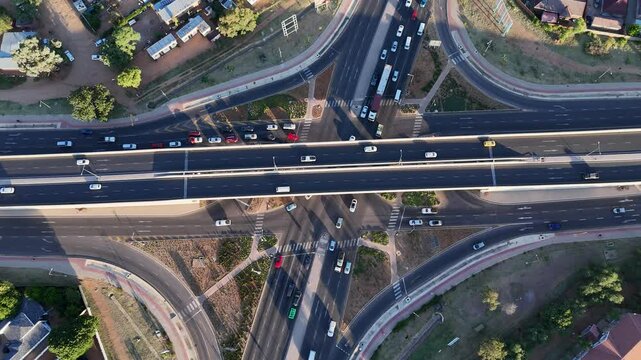 Abstract Art - Gaborone, Botswana at golden hour featuring Urban Traffic Flow across a four-way cross over in 4K High Dynamic Range Quality with Green Vegetation ( ESSTABLISHING DRONE SHOT )