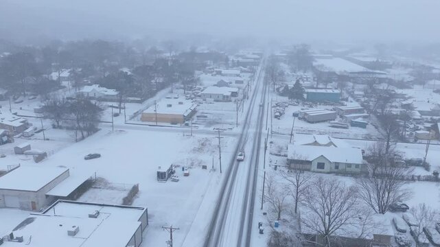 Aerial footage flying over Dodds Ave during a snowstorm in Chattanooga, TN with a car in a ditch.