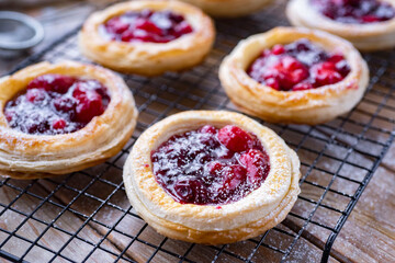 Cheesecakes with berries on a wooden table. Cherry buns for breakfast. Buns with strawberries for dessert. Pies with berries. Close-up