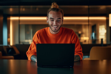 Young man enjoying leisure time while working on laptop in modern interior at night