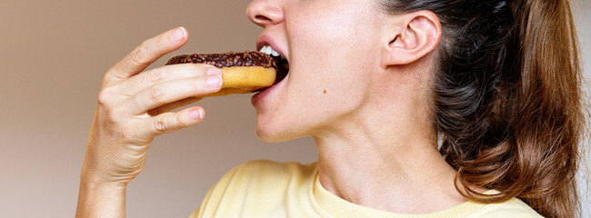 Woman eating chocolate donut side view photo