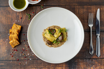 Mushroom ravioli in white porcelain plate on wooden table