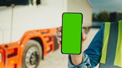 Truck driver holding smartphone mockup of green screen.