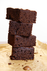Stack of a piece of chocolate brownie placed on brown paper. Close-up stack brownie texture with blur background. Concept of cacao, baking dessert, fudge, sweet tasty, home cook, and rustic kitchen.