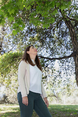 Serene woman enjoying a day in nature looking up. Image with natural light and soft colors. Concept of balance, freshness and well-being