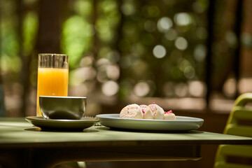 A delicious and colorful breakfast of syrniki pancakes served with fresh berries, a cup of coffee, and a glass of orange juice.