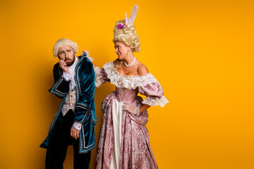 Elegant couple in vintage costumes representing noble figures on a yellow background
