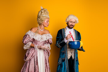 A couple dressed in 18th-century costumes, portraying regal characters on a bright yellow background