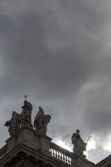 Fototapeta premium Statues on a Historic Building with Dramatic Cloudy Sky Backdrop, Basilica di San Giovanni in Laterano