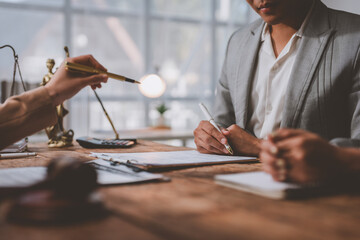 Professionals engaged in a business meeting, discussing documents at a wooden table. Legal scales and a gavel suggest a focus on law or legal advice