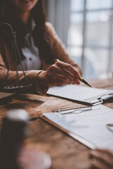 Professional businesswoman in an office setting, reviewing legal documents with a pen in hand. A...