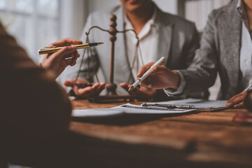 Group of legal professionals engaged in a discussion around a wooden table, with scales of justice...