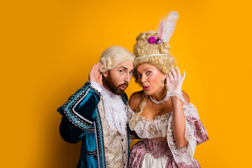 Noble Couple in Classical Costumes Striking a Whimsical Pose Against a Vibrant Yellow Background Highlighting Historical Elegance