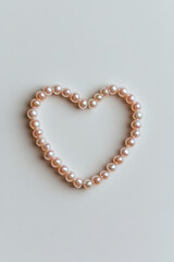 Obraz premium Pink pearls forming heart shape on beige background