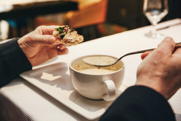 Lunch in a restaurant close-up: soup with bruschetta in a man's hands