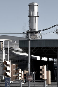 Factory chimney framed by urban elements, emphasizing industrial impact on city landscapes.