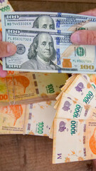 Vertical image of Two pairs of hands exchanging many 1000  peso bills  for two 100 American dollar...