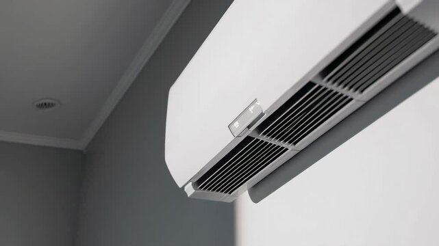 Cool air flowing from sleek white air conditioning unit mounted on gray wall, creating comfortable indoor climate with efficient temperature regulation and healthy ventilation