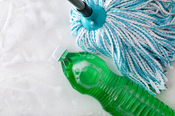Mop and disinfectant on white surface with foam cleaning product