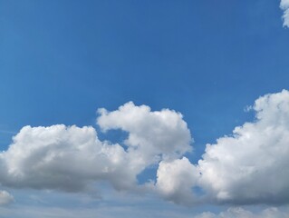 clear blue sky with a few clouds. The sky is very bright and the clouds are scattered throughout. Natural background texture 