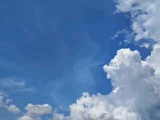 Clear blue sky with a few clouds. The sky is very bright and the clouds are scattered throughout. Natural background texture 