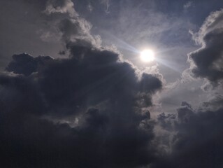 Dramatic dark sky with black stormy clouds before rain as abstract background, extreme weather, the sun shines through the clouds