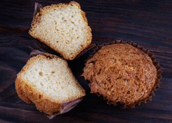 Cut and whole cupcake on dark wooden background.