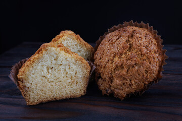 Cut and whole cupcake on dark wooden background.
